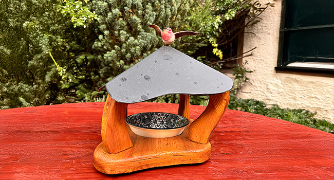 Mangeoire à oiseaux en bois sculpté, surmontée d'un petit oiseau